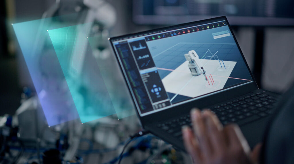 A person is interacting with a laptop displaying a 3D model of a robotic arm in a technology-focused environment.