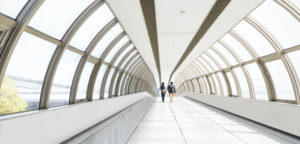 Rear view of people walking on modern skybridge walkway